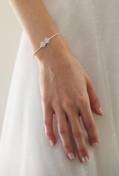 a woman's hand wearing a white dress and diamond ring on her left wrist