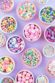 small bowls filled with candy and sprinkles on a purple tablecloth,