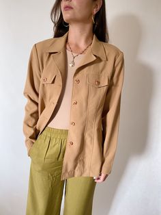 1980s Hennes beautiful camel safari style jacket perfect for summer/spring season  - Brand: Hennes - Made in Sweden - Composition 100% polyester  - Closed with buttons - 2 pockets with buttons on the chest Model is 168 cm height. Retro Single Breasted Beige Blazer, Vintage Khaki Blazer For Fall, Retro Single-breasted Beige Blazer, Retro Beige Single Breasted Blazer, Retro Beige Single-breasted Blazer, Beige Button-up Summer Blazer, Summer Beige Button-up Blazer, Vintage Khaki Spring Blazer, Vintage Beige Outerwear For Summer