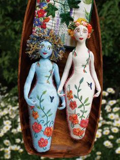 two dolls are sitting in a boat with flowers on the bottom and one is blue