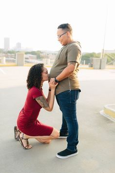 a woman kneeling down next to a man in a parking lot