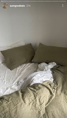 an unmade bed with white sheets and pillows