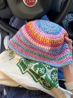 a person is holding a colorful hat in their hand while sitting in the driver's seat