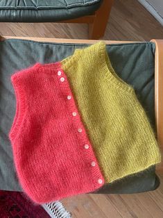 two knitted sweaters sitting on top of a chair