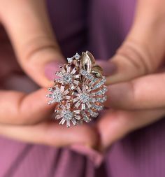 a close up of a person holding a ring in their hands with diamonds on it