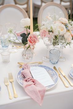 the table is set with plates, silverware and pink napkins for an elegant wedding reception