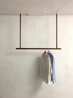 two shirts hanging on a clothes rack in an empty room