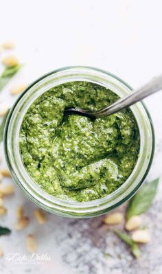 a jar filled with green pesto and topped with a spoon