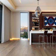 an open kitchen and dining room with wood flooring, white counter tops and bar stools