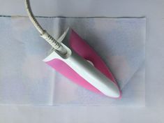 a pink and white hair dryer sitting on top of a piece of paper