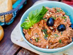 a blue bowl filled with food sitting on top of a wooden table next to bread