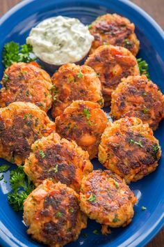 several crab cakes on a blue plate with sour cream and parsley in the background