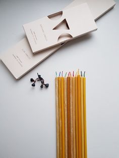 several yellow pencils are next to a pair of scissors and some black beads on a white surface