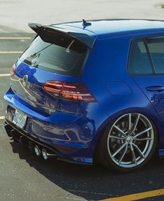 the back end of a blue car parked in a parking lot