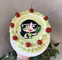 a person holding up a cake decorated with cartoon characters on it and cherries around the edges