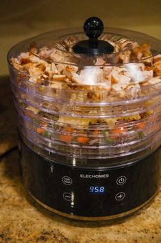 an electric food cooker filled with lots of different types of food on top of a counter