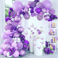 purple and white balloons are hanging from the ceiling in front of a wall with butterflies on it