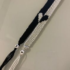 a black and white beaded belt with tassels hanging from it's side