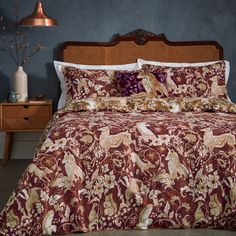 a bed with red and gold bedspread in a blue room next to a dresser