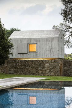 a house with a pool in front of it and a stone wall next to it