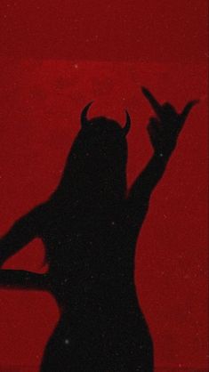 the silhouette of a woman with horns on her head is shown in front of a red background