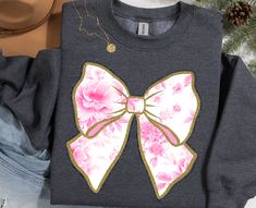 a t - shirt with a pink bow on the front and blue jeans behind it