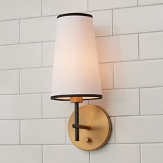 a wall light with a white shade on it's side against a white brick wall