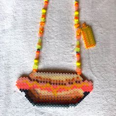 a beaded hot dog with mustard and ketchup on it hanging from a string