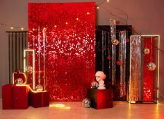 red and silver decorations are on display in front of a red wall with shiny sequins