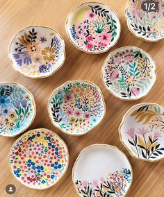 six small bowls with flowers painted on them sitting on a table top next to each other