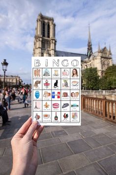 a person holding up a card that says bingo in front of a castle like building