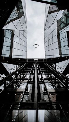 an airplane is flying in the sky between two buildings that have glass balconies