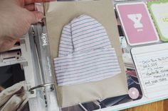 someone is cutting out a baby's hat on top of a book with scissors