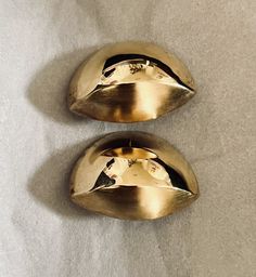 two shiny gold metal objects sitting on top of a white surface