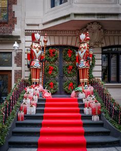 a red carpeted staircase leading up to an entrance with two statues on either side