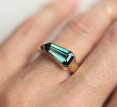 a woman's hand with a ring that has two green stones on the side