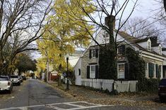 an old house with ivy growing on it's side and cars parked in front