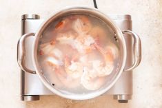 a pot filled with shrimp and broth sitting on top of a stove burner