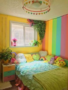 a bedroom decorated in rainbow colors with stuffed animals on the bed and plants hanging from the ceiling