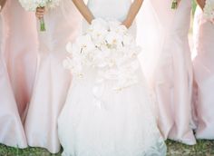 two bridesmaids holding bouquets in front of their faces and wearing pink dresses