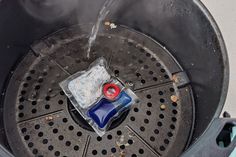 a blue and red object sitting on top of a metal grate with water coming out of it