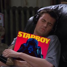 a man laying in a chair while holding a book with the title starboy on it