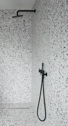 a bathroom with a black shower head in the corner and speckled wallpaper on the walls