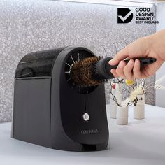 a person is using a brush to clean the hair on top of a toaster