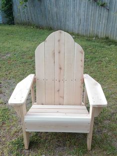 a wooden chair sitting on top of a grass covered field