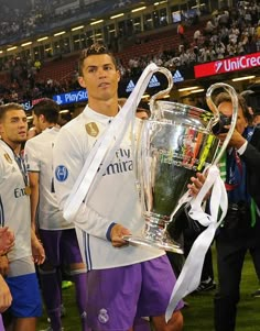 the soccer player is holding his trophy in front of him and other players around him