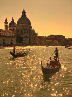 two gondolas are in the water with buildings in the backgrouds