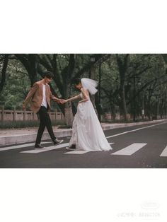 a bride and groom crossing the street holding hands