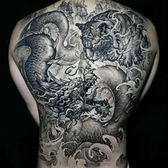 the back of a man's body covered in black and white ink with dragon tattoos on