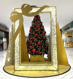 a christmas tree in a gold frame with red ornaments and bows on the top is surrounded by other decorations